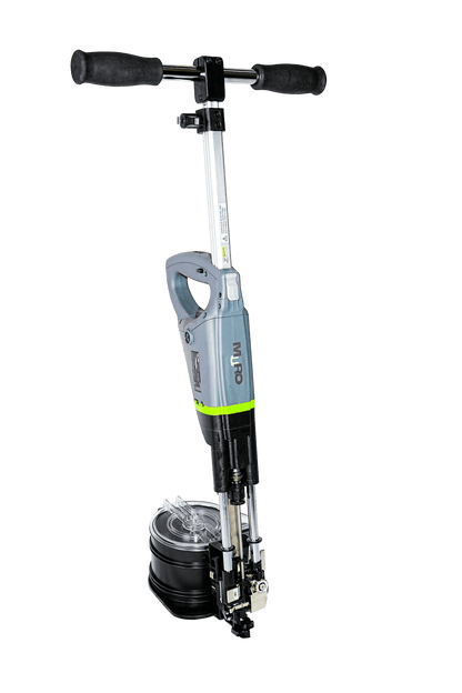 A cordless stump grinder with a T-handle and a circular cutting drum, shown against a solid green background. The product features a gray and black body with a bright lime green accent band.