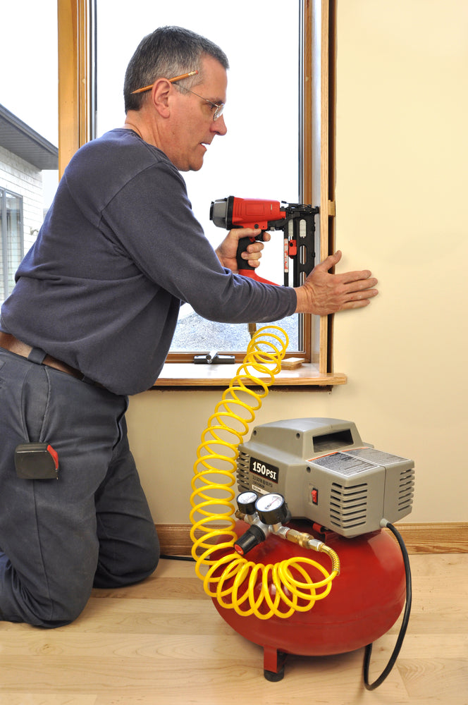 Man using a nail gun with an air compressor in a home improvement setting